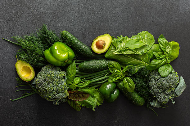 istock A vibrant assortment of fresh green vegetables is carefully arranged on a dark surface. This selection includes broccoli, green bell peppers, cucumbers, spinach, lettuce, and an avocado, healthy eating 2240312876