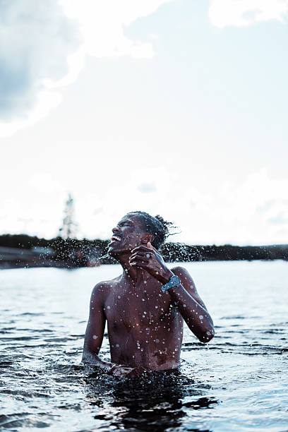 A young black man enjoys swimming and splashing in the cool water of Yellowstone Lake in Yellowstone National Park, Wyoming, USA, on a warm summer afternoon.