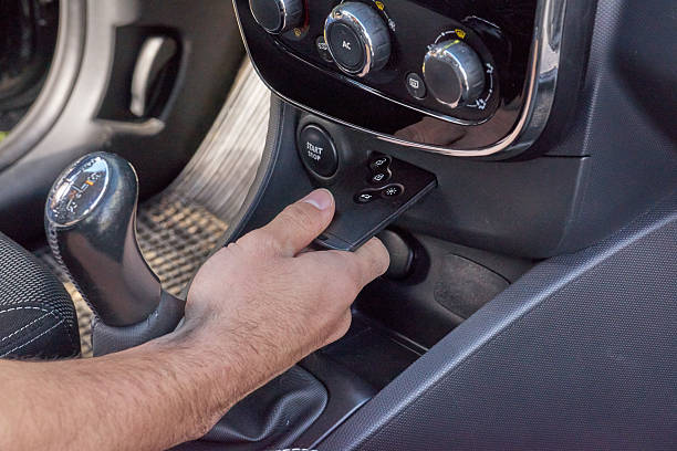 Male hand holds keyless remote by dashboard and start controls in modern car interior, secure entry and ignition concept: Tallinn, Estonia - May 7, 2019