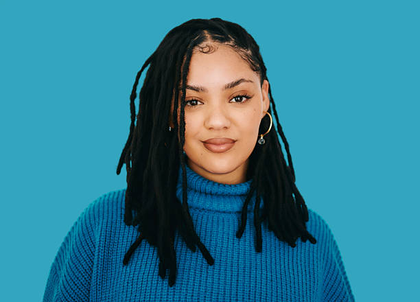 istock Confident young Black woman wearing blue sweater against solid blue background portrait 2240316548
