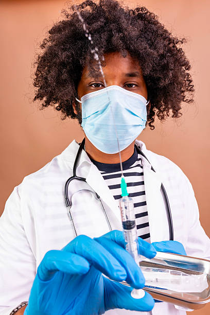 Healthcare professional wearing a face mask and gloves preparing a syringe