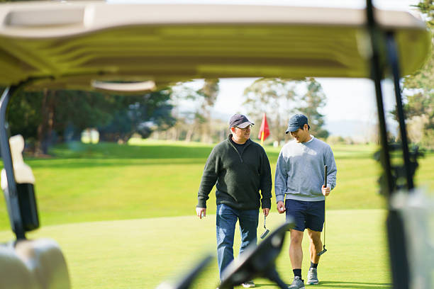 istock Two golfers walk toward a golf cart while chatting on golf course. 2240326061