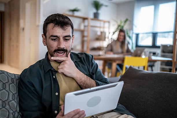 istock Young man having video call on tablet at home 2240329980