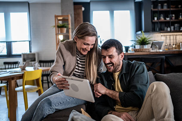 istock Couple laughing while enjoying digital tablet at home 2240330001