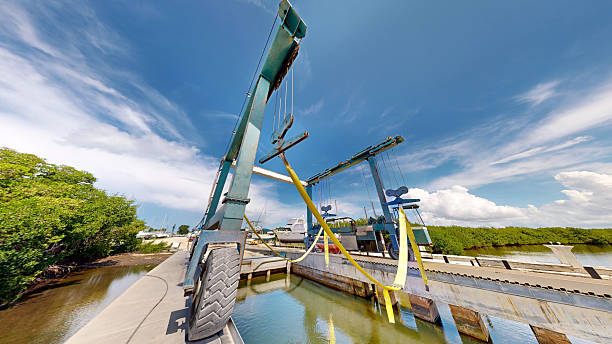Nodu Pianu - Sardinien - Italien - 02-23-2025: Upward view of a blue boat hoist at Palau Marina with numbered beams and ropes silhouetted against a bright sky with thin wispy clouds and sunlight.