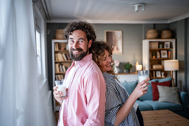 istock Happy couple enjoying milk while standing back to back at home 2240335244