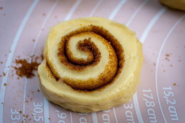 An appetizing close-up of raw, unbaked sweet pastry swirled with cinnamon sugar. Shallow depth of field highlights the texture of this delicious comfort food