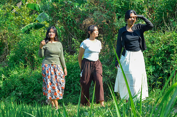istock Three girls explore the narrow tropical rice field path under bright sunlight 2240346751