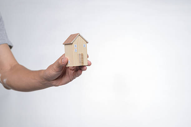 istock Hand Holding Small Wooden House Model Against Neutral Background 2240347609