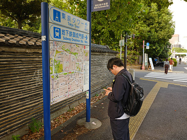 Tokyo, Japan - October 10, 2025: A man reading a local area street map near Tokyo Tower in Tokyo, Japan.