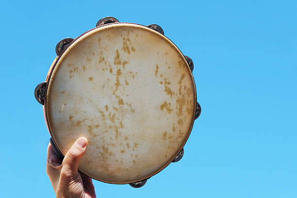 Tambourine in hand against blue sky