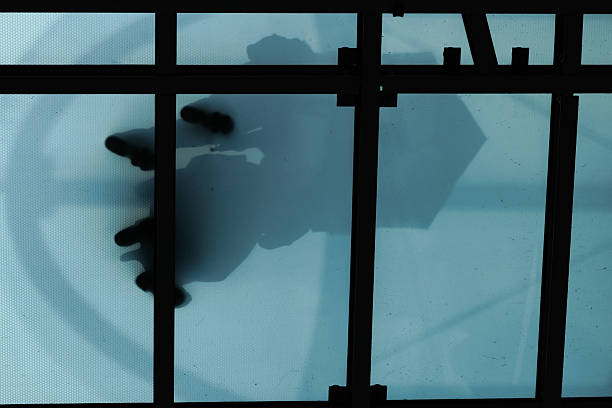 istock Umbrella Holding Silhouettes on Teal Colored Glass Ceiling 2240360028