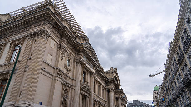 A crane is seen near the historic Bourse building in Brussels, Belgium, under a cloudy sky.