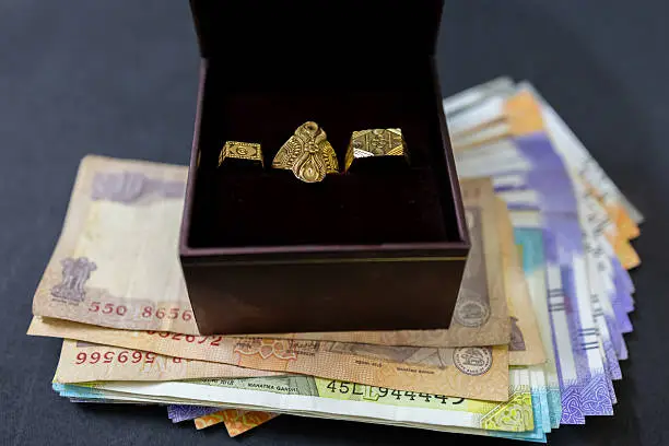 Photo of Elegant ring collection arranged in box over currency notes symbolizing prosperity