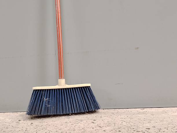 A Broom against a plain gray wall with copy space.