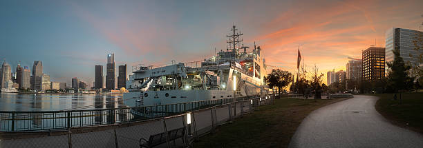 A Canadian Navy ship is shown moored in Windsor, Ontario.   Detroit Michigan can be seen across the Detroit river.
