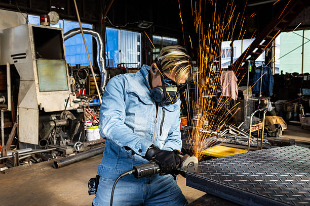 A professional metal worker is grinding a diamond plate steel sheet with sparks flying.