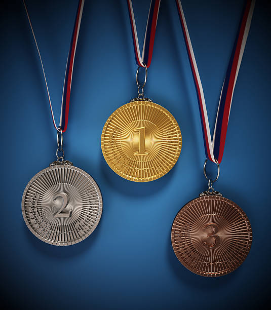 istock Three medals representing first, second, and third place hanging on ribbons against a blue background 2240375381