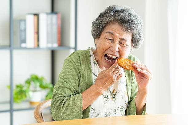 istock Senior woman eating rice crackers 2240375565