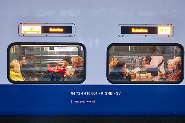 Modern double-decker train at station platform with passengers visible through windows. People traveling between Serbian cities, Subotica and Novi Beograd. Urban transport, commuting, and railway travel lifestyle in Europe