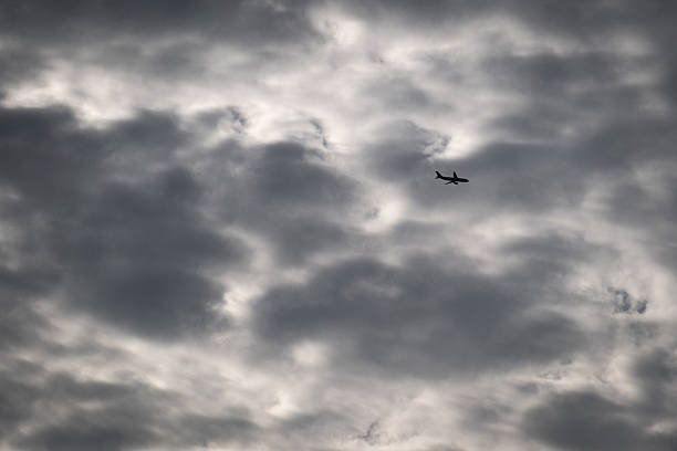 istock Silhouette of a passenger plane in the sky covered with gray clouds. 2240384887