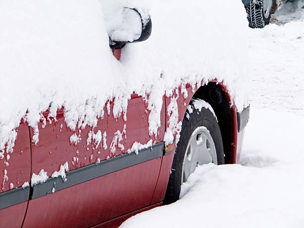 HAVIROV, CZECHIA - MAY 19, 20211: Snowy red car parked in heavy blizzard and covered in snow