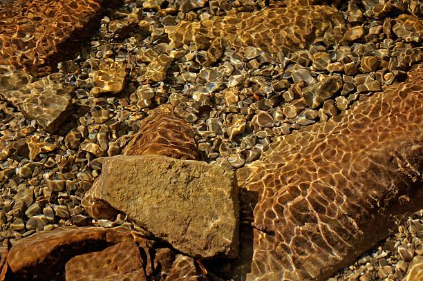 Colourful stones in cold autumn river with clean water and ripples