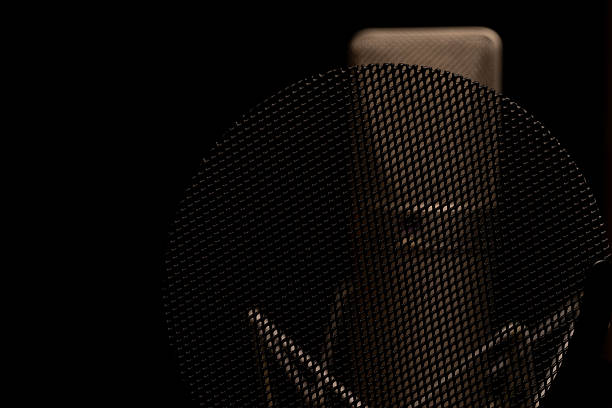 Close-up of a Professional Microphone in a Recording Studio with Dark Background and Mesh Pop Filter