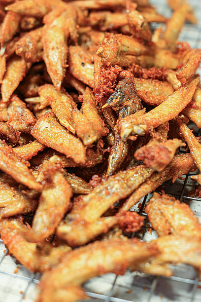Vertical view of crispy Thai Fried Chicken Wing Tips on a rack. Golden-brown, crunchy street snack. Perfect appetizer for social media.