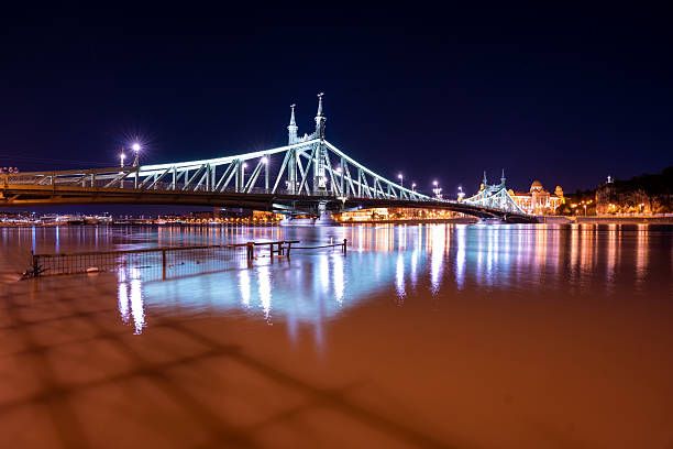 Budapest, Hungary - September 20, 2024: Liberty Bridge illuminated above flooded Danube waters at night