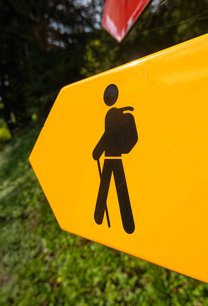 Yellow hiking trail sign with black hiker icon