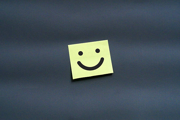istock A yellow sticky note with a simple happy smiley face on a dark gray background 2240401353