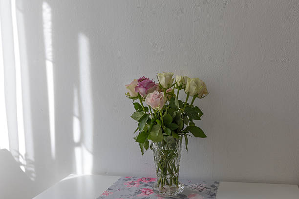 istock Pastel colored roses in a vase on a table 2240401730