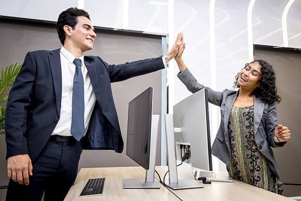 istock Young businesspeople make high five hand touch over desktop computer in office. Two business staff colleagues greet with hi five. Businessman and businesswoman do high five to celebrate the success. 2240406763