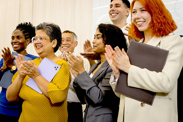 istock Group of diverse businesspeople clapping hands in admiration while standing together. Happy cheerful business multiethnic coworkers clap hands to celebrate the success. Smiling confident business team 2240406919