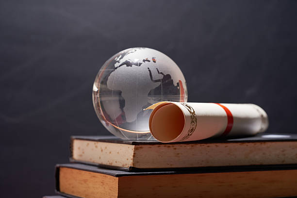 istock glass globe with scoll of certificate on books 2240407611
