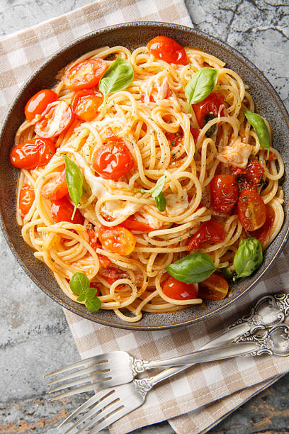 Margherita Spaghetti made with tomatoes, basil, and mozzarella closeup on the plate. Vertical top view