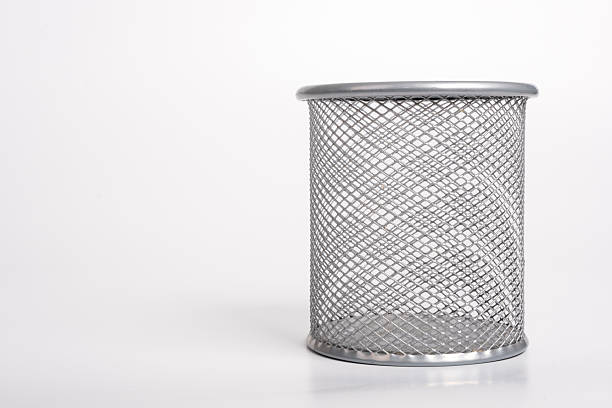 A clean, minimalist close-up captures a sturdy metal pen holder (or desk cup), presented upright and sharply isolated against a pure white background. The object is empty, emphasizing its function as a container for organization or, metaphorically, as a small waste bin or basket for paper. This focused composition serves as an ideal graphic for themes of office supplies, productivity, and workspace organization, with ample surrounding copy space for text or branding.