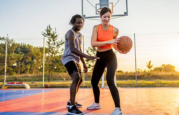 istock Couple playing basketball outdoors at sunset 2240409479