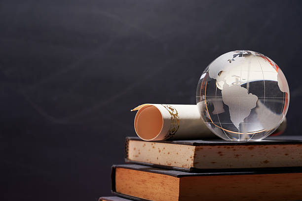 istock glass globe with scoll of certificate on books 2240409523