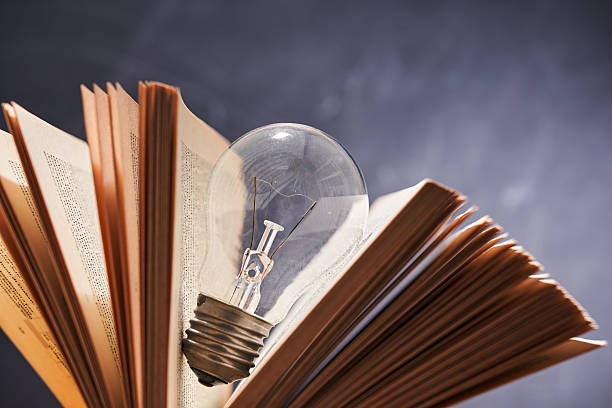 light bulb and black hardcover book against chalkboard