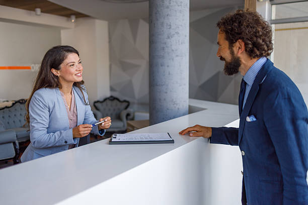 istock Woman helping man checking in at reception desk 2240415629