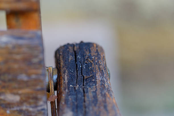 A detailed view of aged wooden planks arranged diagonally, featuring cracked surfaces and peeling red paint. The texture emphasizes natural weathering and timeworn materials. Ideal for backgrounds, rustic design themes, or material surface references. No people present.