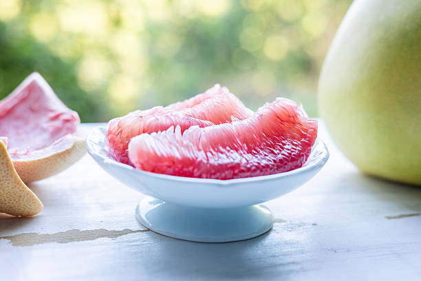 Red Grapefruit slices in a black bowl on black background. Close-up.