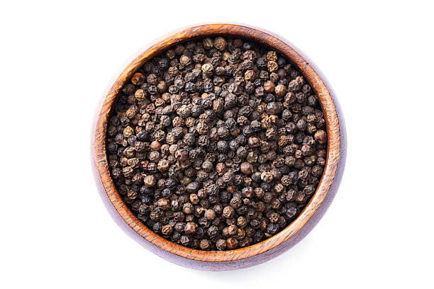 istock Black peppercorns on white background 2240436703