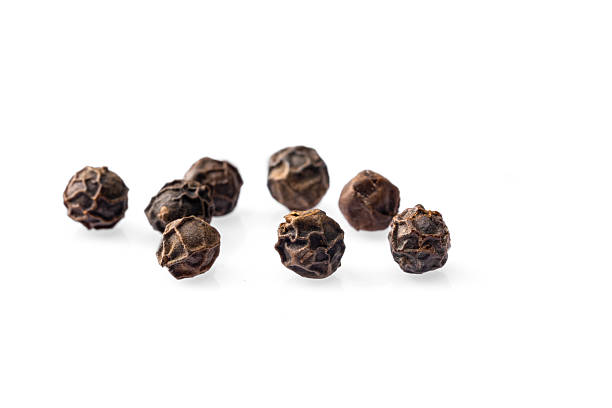 Black peppercorns on white background