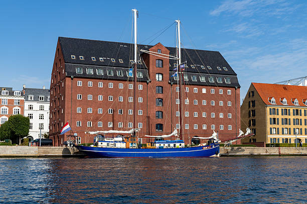 moored boat with Danish flag and reflection on the water of the waterway