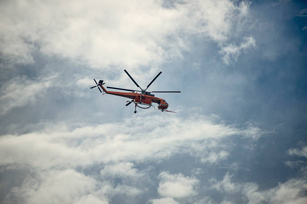 Los Angeles de San Rafael, Spain - July 30, 2020: A Spanish firefighter helicopter AgustaWestland AW119Ke Koala (EC-LPK) with a basket of water flies on a forest fire.