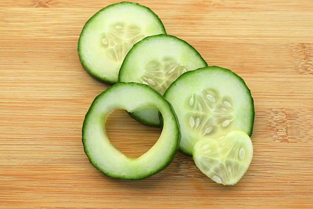 Cucumber slices with heart shaped cutout, wooden background
