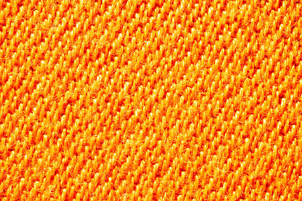 Macro image of vibrant orange woven textile with visible threads and fuzzy fibers.